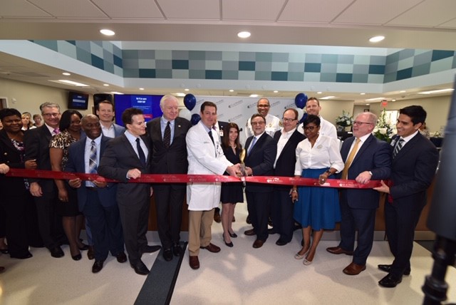 Doctors and business representatives posing with scissors at a ribbon cutting ceremony