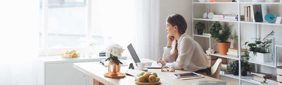 girl sitting at her desk working with beautifully organized shelf behind her