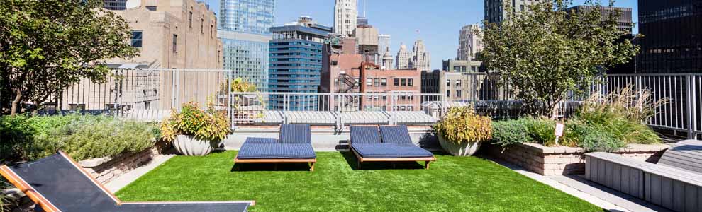 green roof in a city with lounge chairs and plants on it