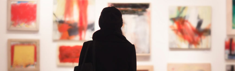 shadow of a woman looking at a wall of art in a gallery