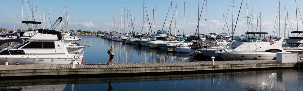 Oakville waterfront with boats docked and woman walking across a long dock
