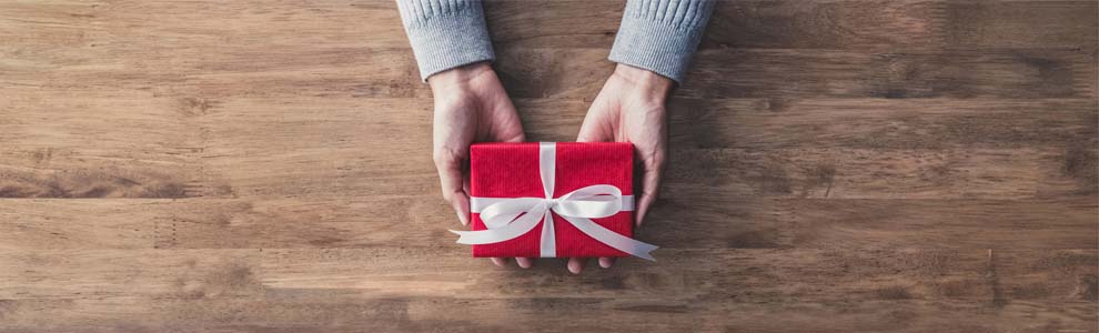person's hands holding small red gift with white bow
