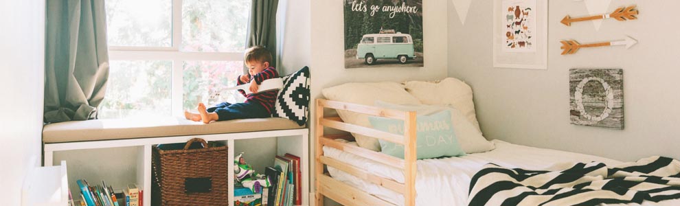 litte boy sitting in organized bedroom
