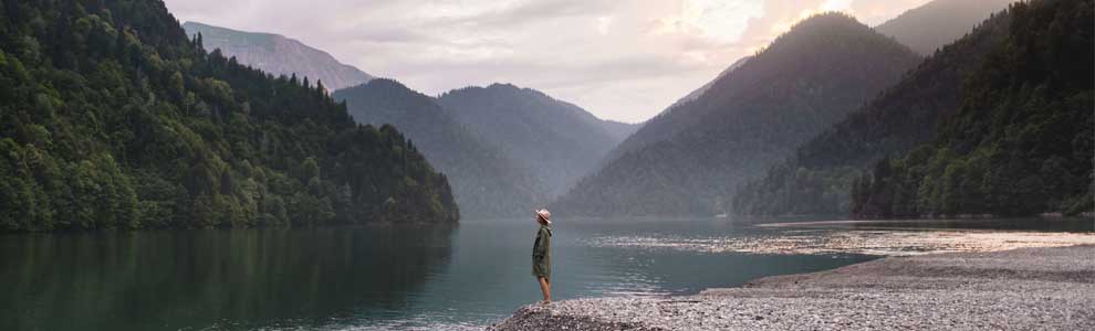 girl standing beside a lake and mountains