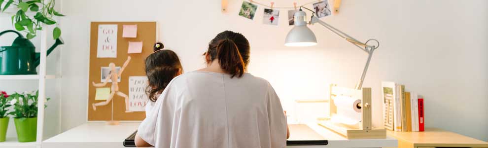 mother and daughter sitting at a desk reading